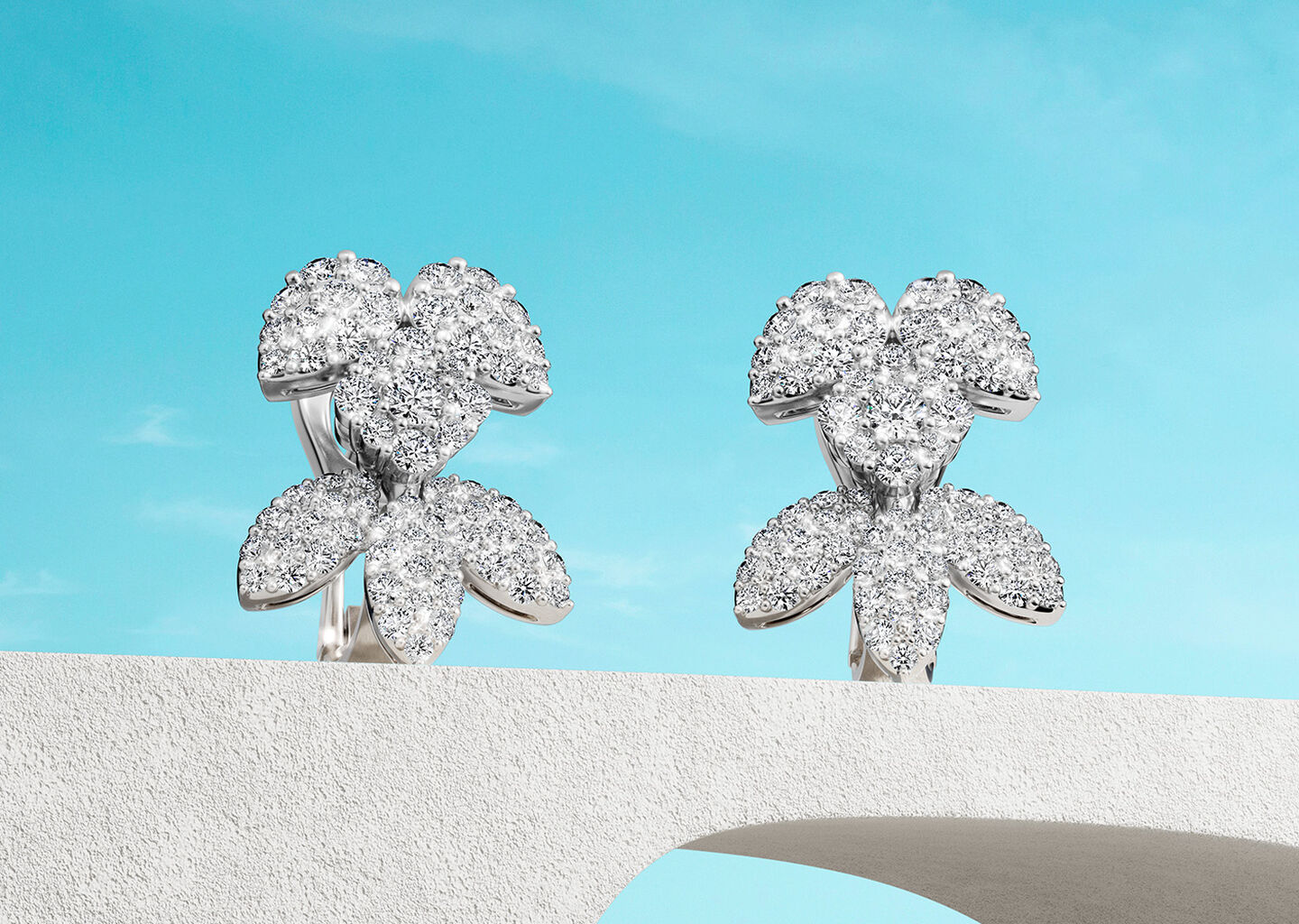 Birks Snowflake Snow Angel diamond earrings on a blue background.